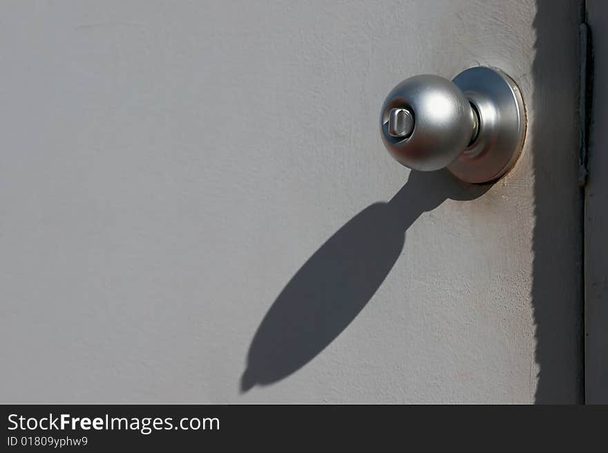 Grungy looking grey metal door with doorknob in bright sunshine