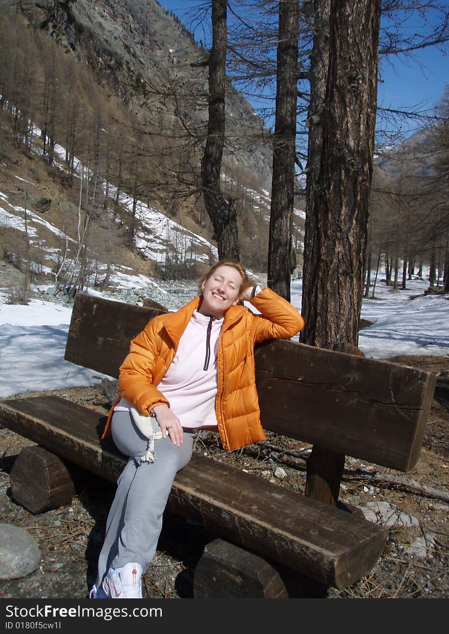 A girl resting in the Alps, on the benche with face to the sunbeams. A girl resting in the Alps, on the benche with face to the sunbeams