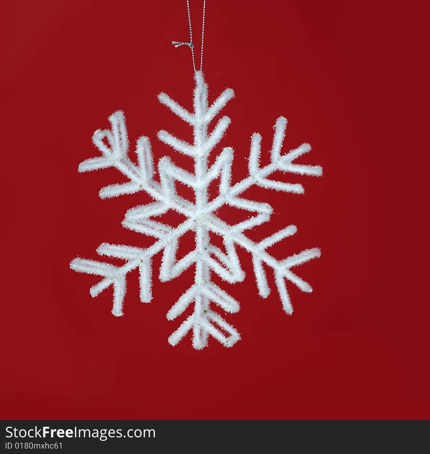 Beautiful close up of a Glittery white hanging star ornament on red background