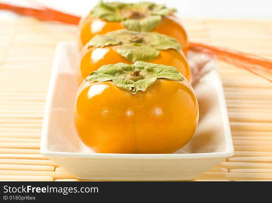 Three fresh ripe persimmons presented in a row. Three fresh ripe persimmons presented in a row.