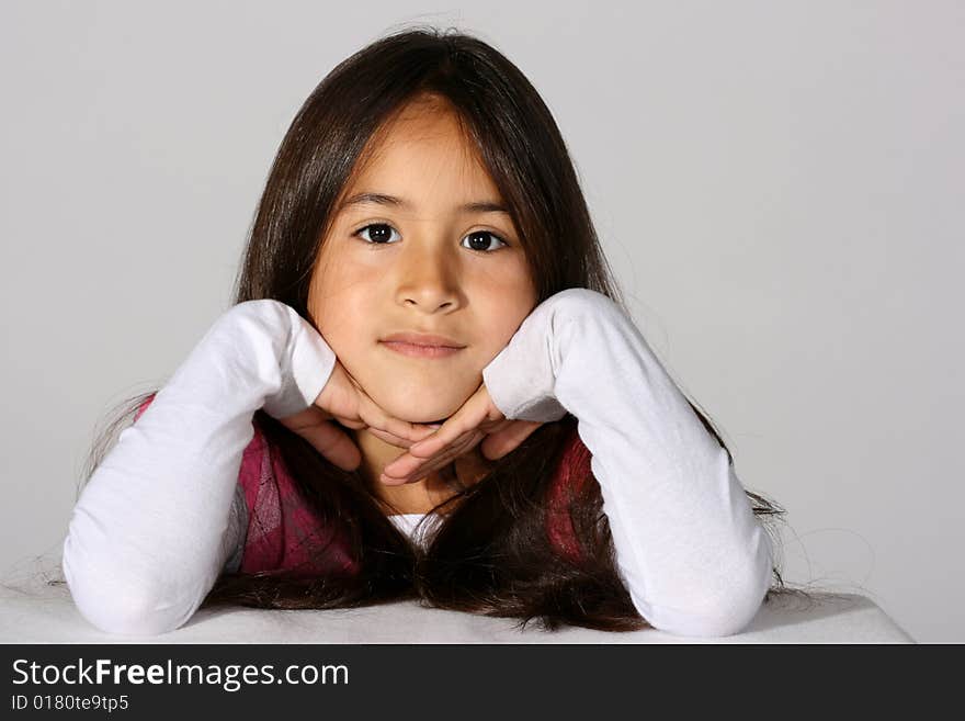 Cute young hispanic girl with her head propped up in her hands