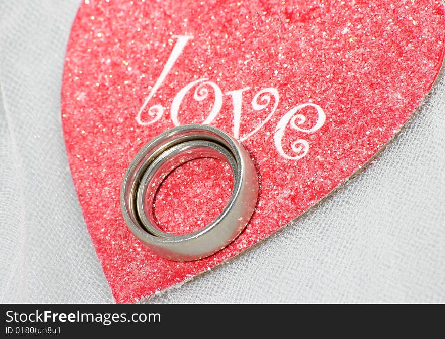 Wedding bands nested on top of a red heart saying love