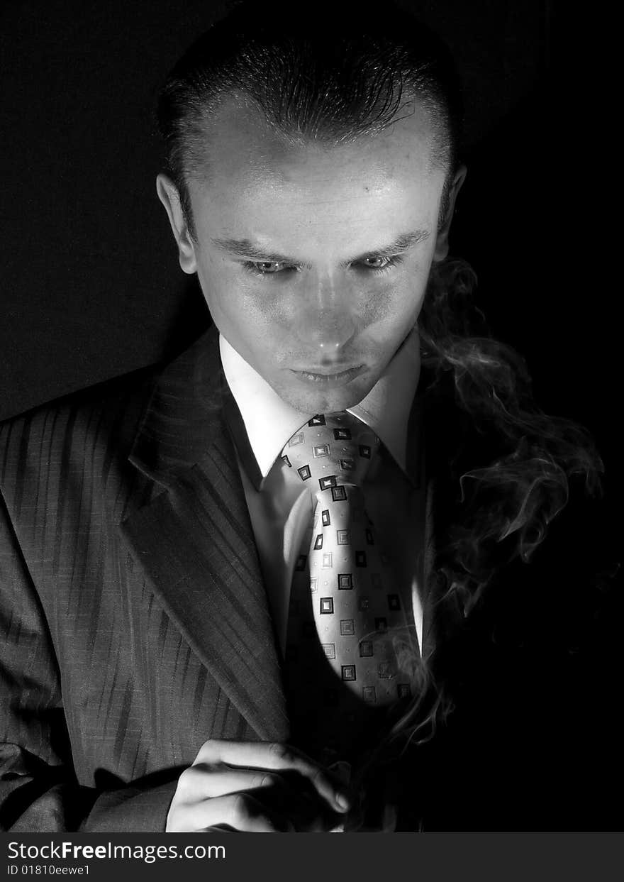 Young man in suit smoking cigarette looking down. Young man in suit smoking cigarette looking down