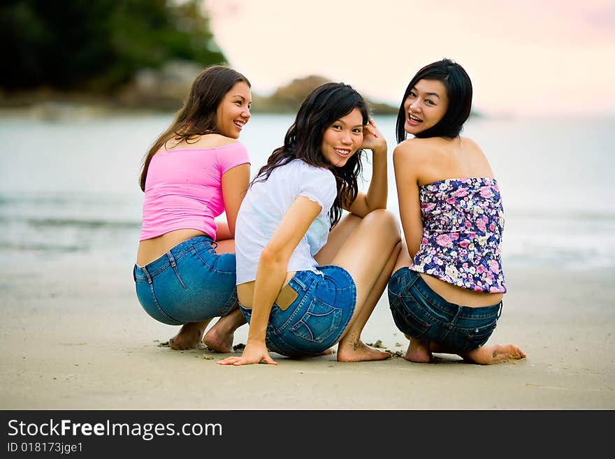 Group of happy asian woman friends squatting by the sunset beach. Group of happy asian woman friends squatting by the sunset beach