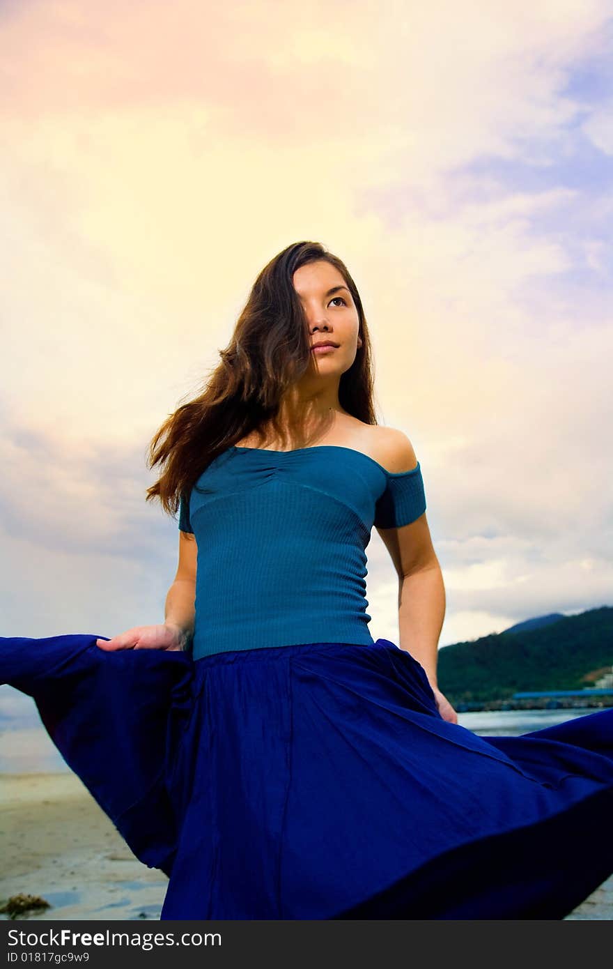 Young eurasian woman at the sunset beach turn and flipping her skirt