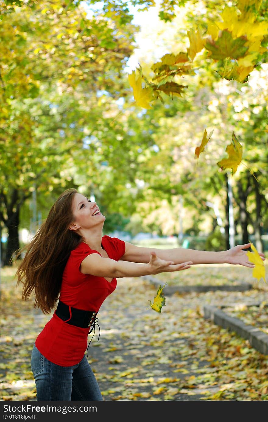 Young happy woman in red throw the maple leaf. Young happy woman in red throw the maple leaf