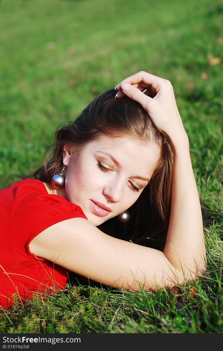 Beautiful young woman in red lying on the green grass. Beautiful young woman in red lying on the green grass