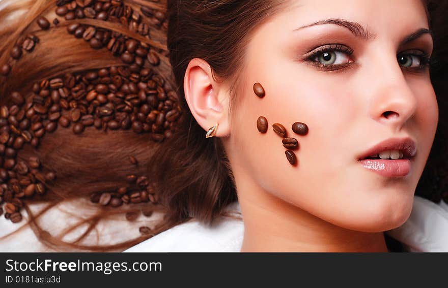 Coffee beans on the hair and face of beautiful young woman. Coffee beans on the hair and face of beautiful young woman