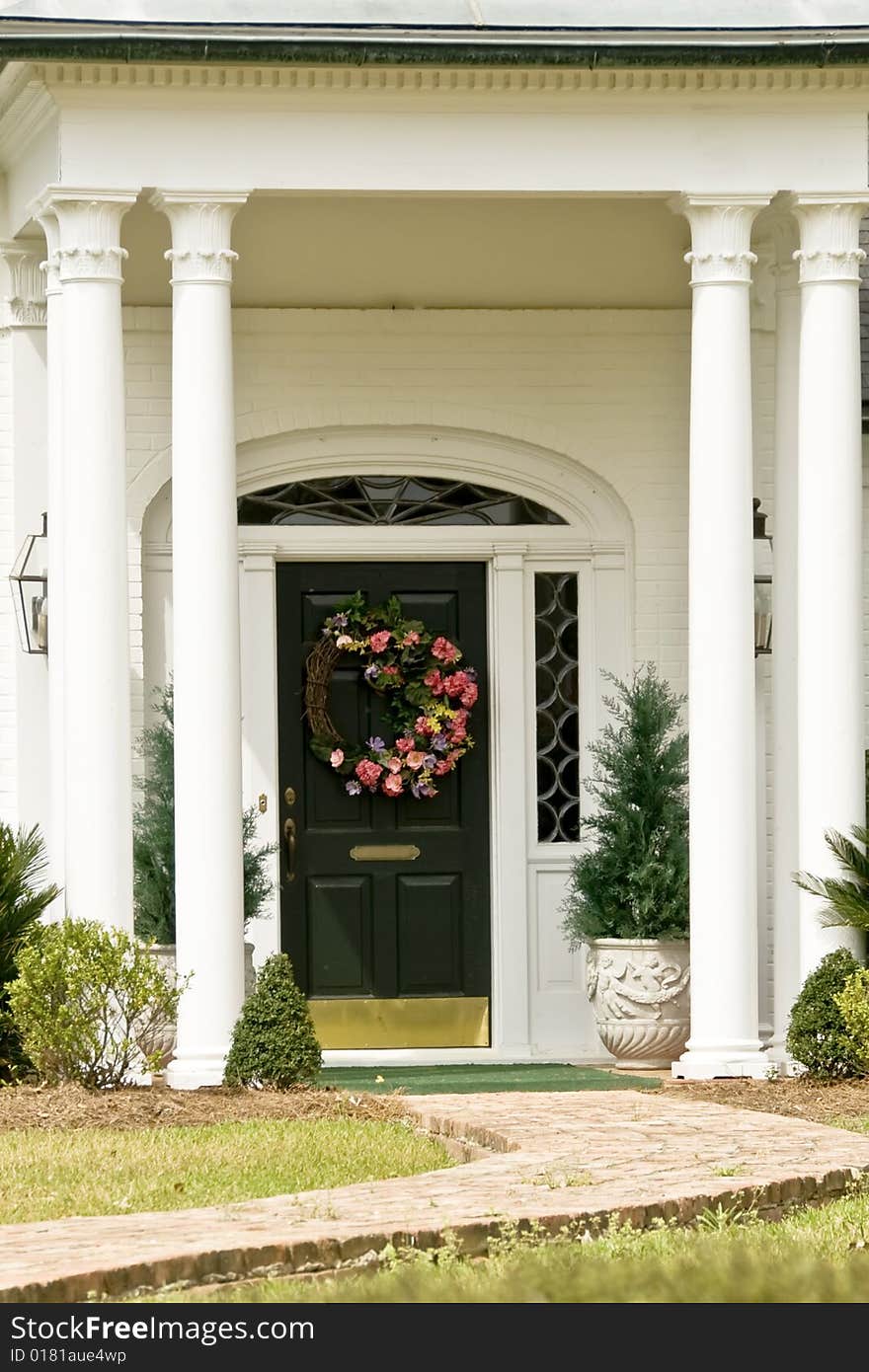 A black door with a wreath graced with columns. A black door with a wreath graced with columns.