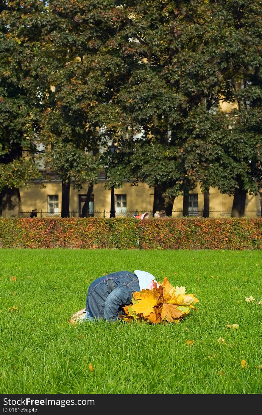 Little girl at maple yellow leaves on her head. Seats at green grass. Little girl at maple yellow leaves on her head. Seats at green grass.