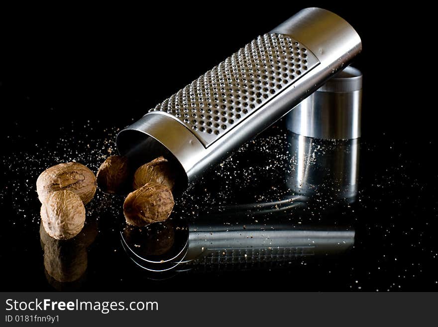 Nutmeg and silver grater on black background