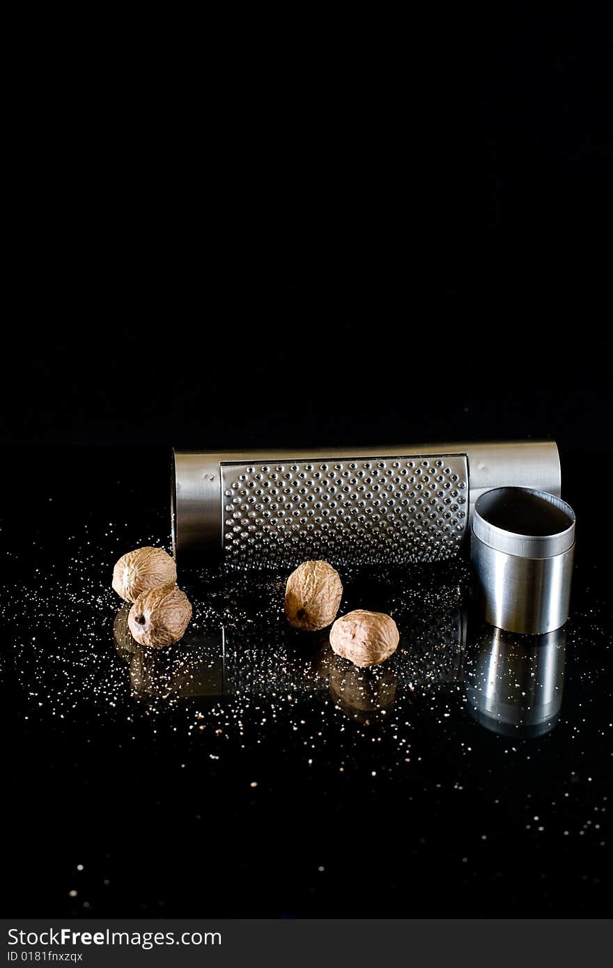 Nutmeg and silver grater on black background