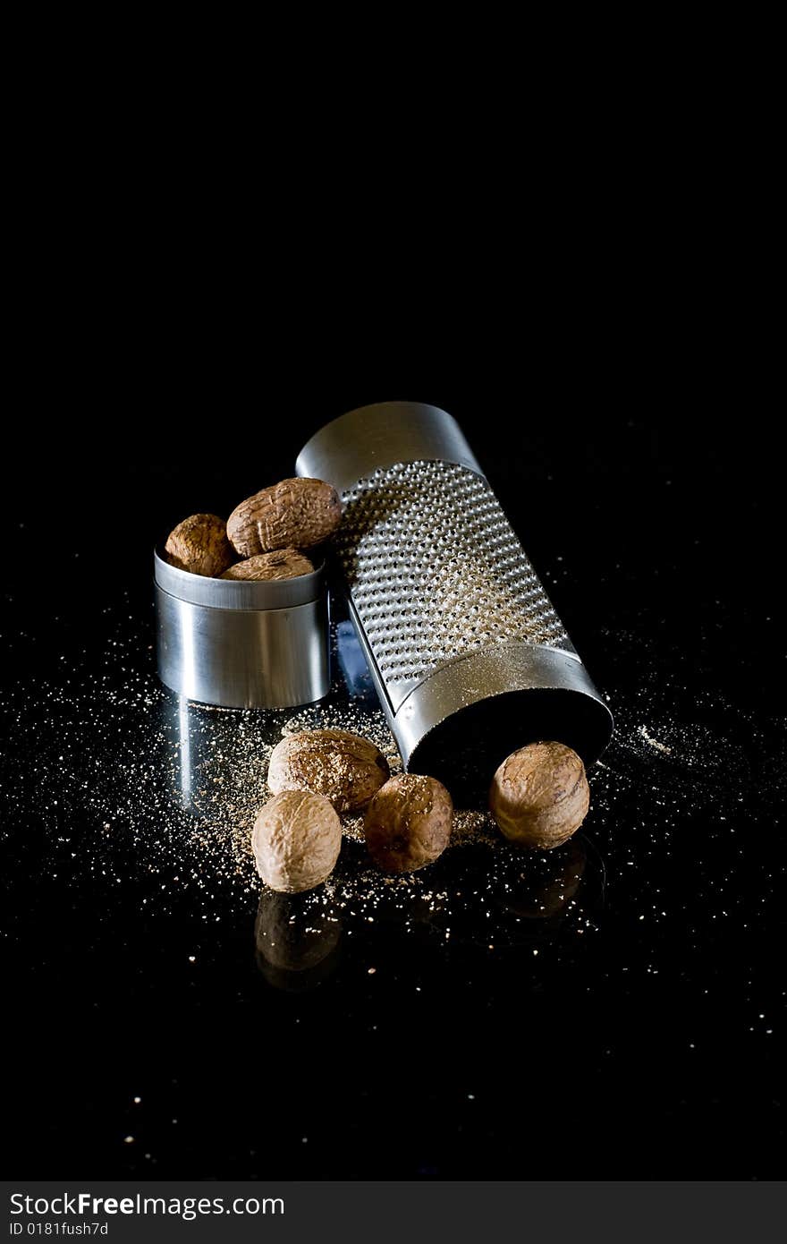 Nutmeg and silver grater on black background