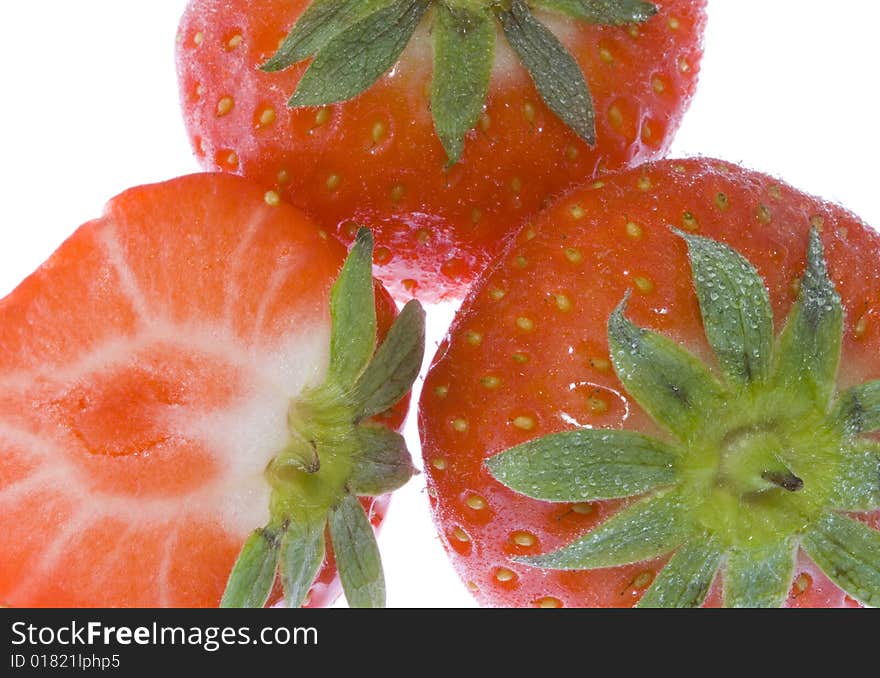 Three strawberries (one cut) on the white background