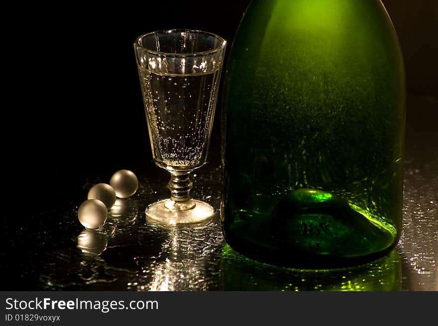 Glass with champagne and green bottle. Glass with champagne and green bottle