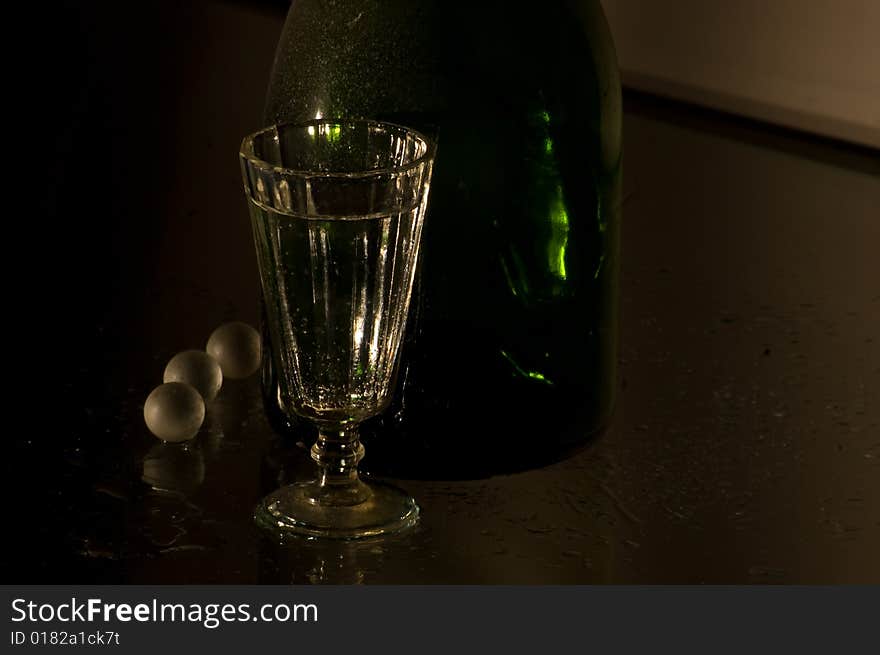 Glass with champagne and green bottle. Glass with champagne and green bottle