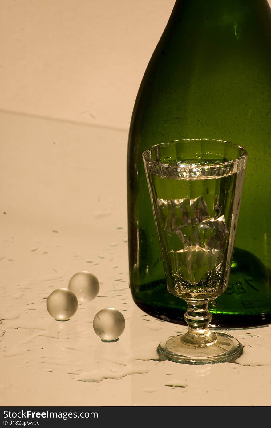 Glass with champagne and green bottle. Glass with champagne and green bottle