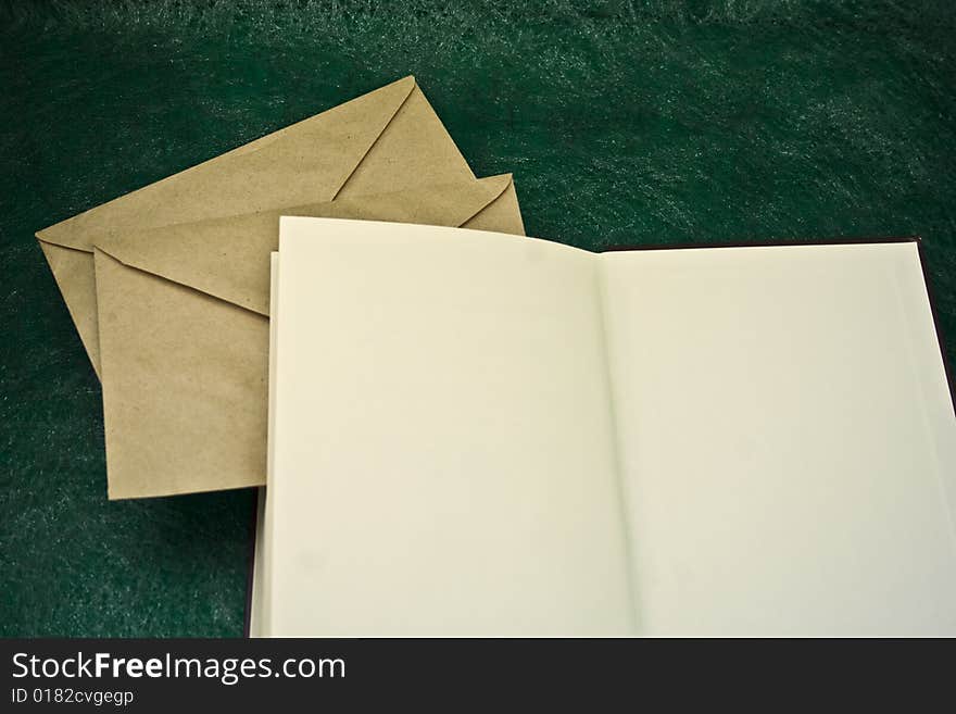 Open book and envelopes on a green background