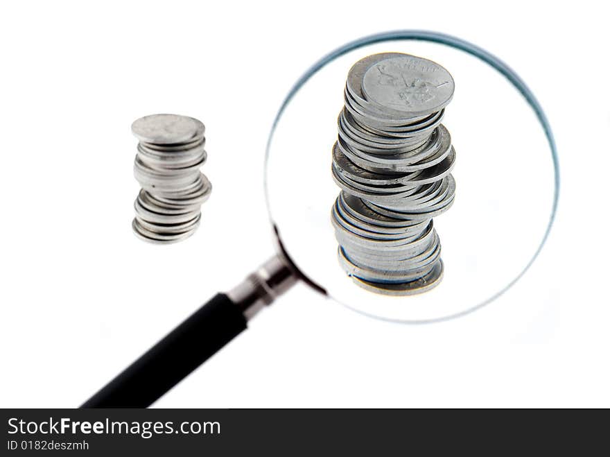 Magnifying glass with a two small columns of coins behind it. Magnifying glass with a two small columns of coins behind it.