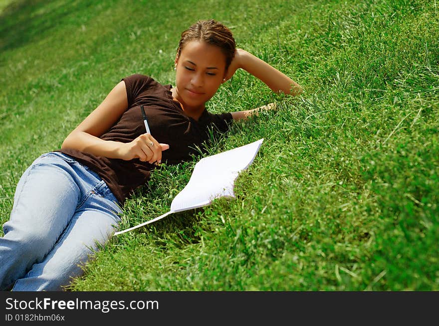 Beautiful young woman in green field with notebook. Beautiful young woman in green field with notebook.