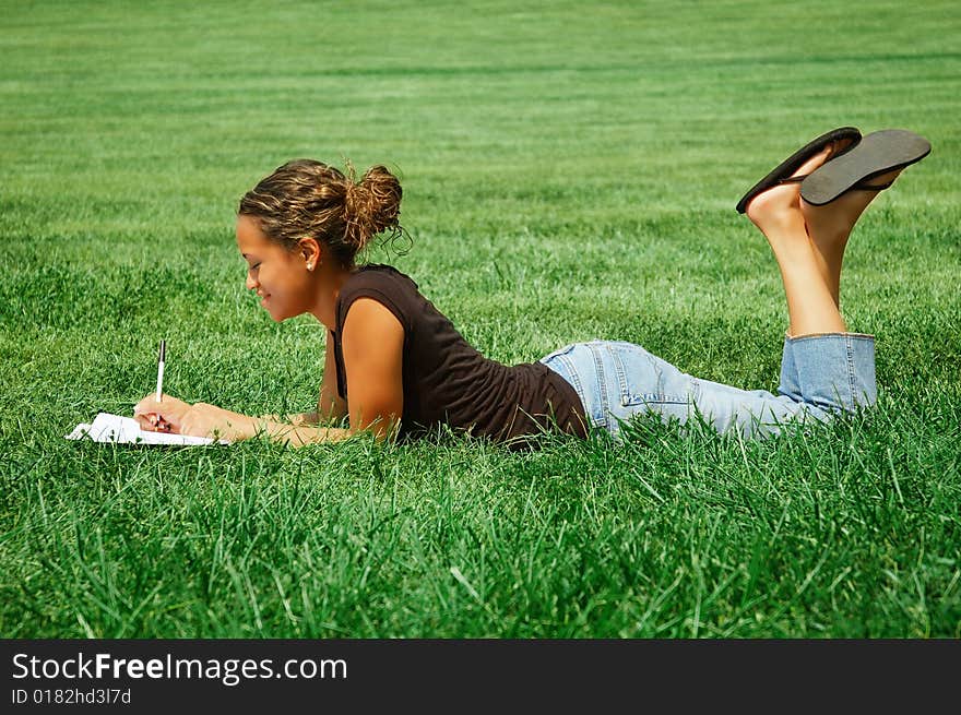 Beautiful young woman in green field with notebook. Beautiful young woman in green field with notebook.