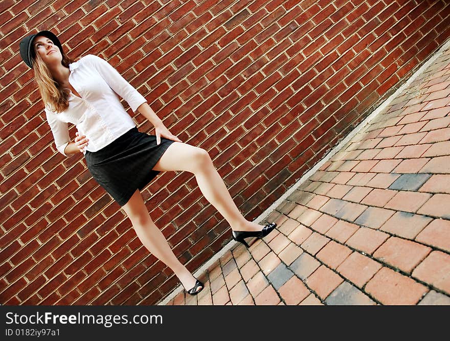 Fashionable young woman posing in front of a brick wall. Fashionable young woman posing in front of a brick wall.