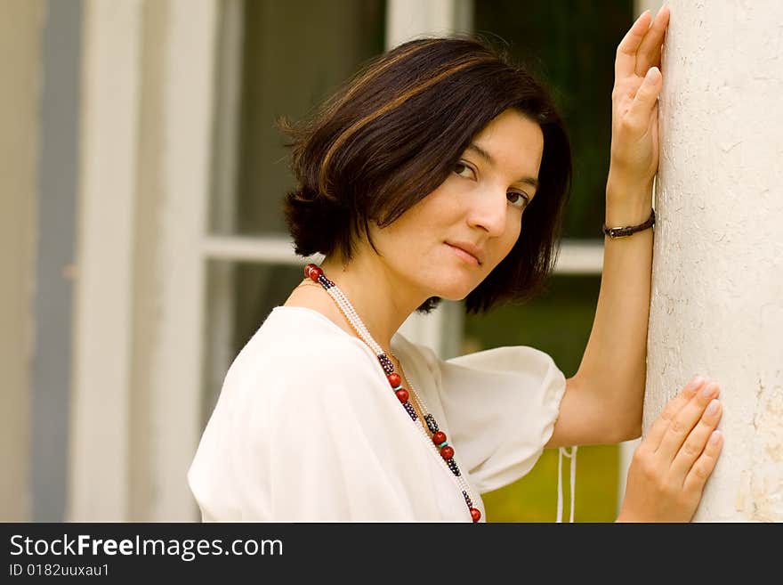 Portrait of dreaming pretty woman standing near white column