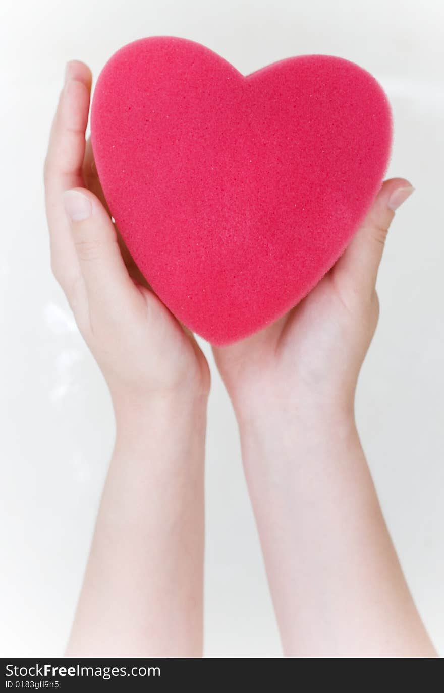 Heart sponge in hands in the bath