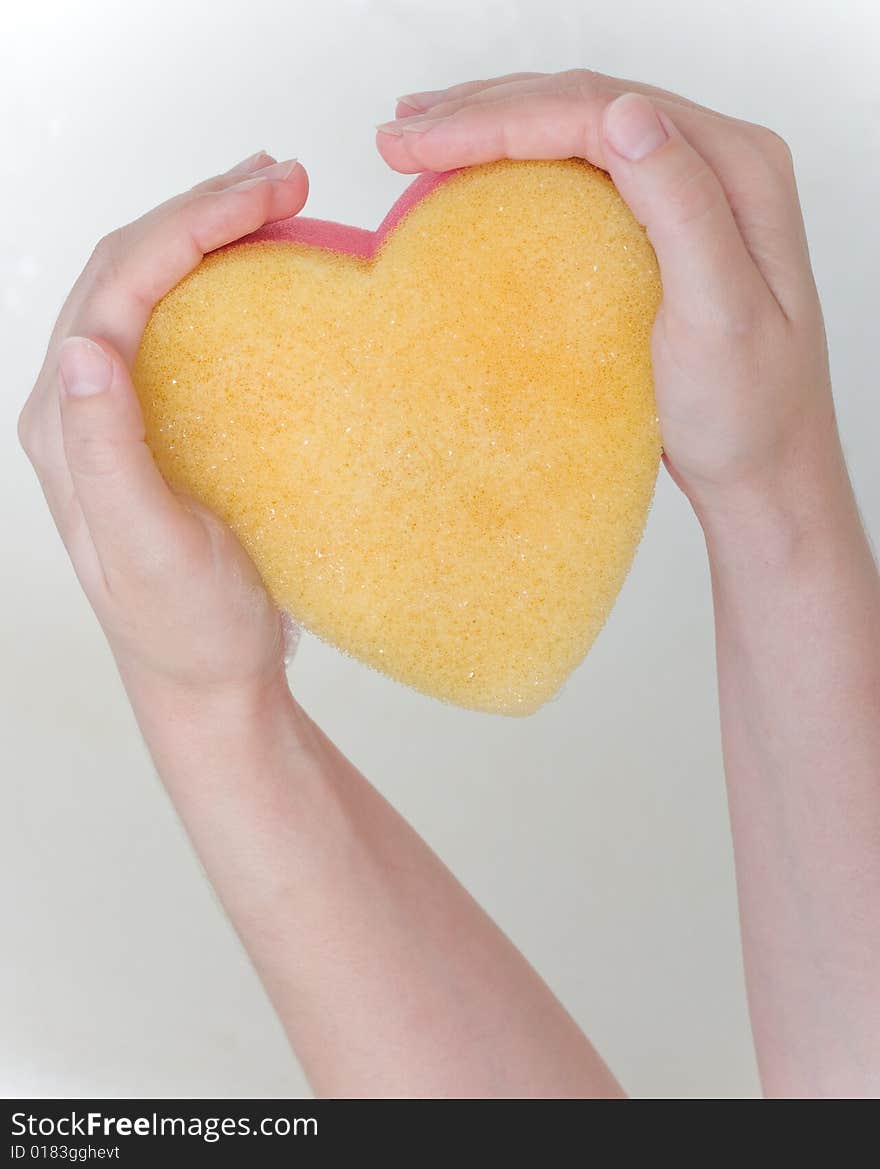 Heart sponge in hands in the bath