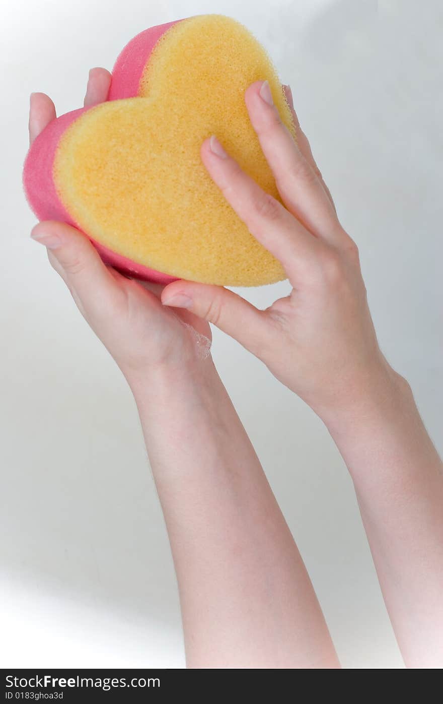 Heart sponge in hands in the bath