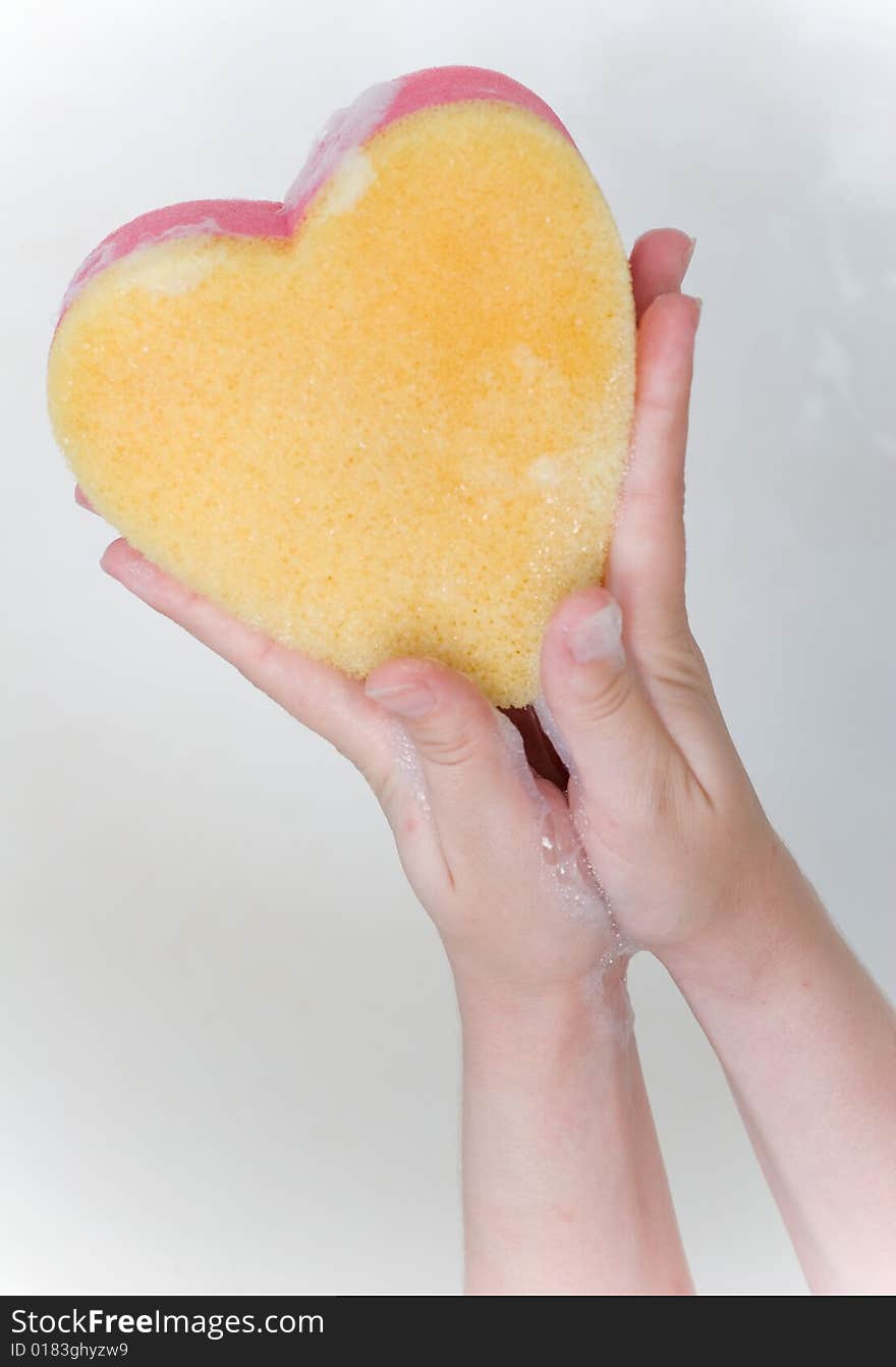 Heart sponge in hands in the bath