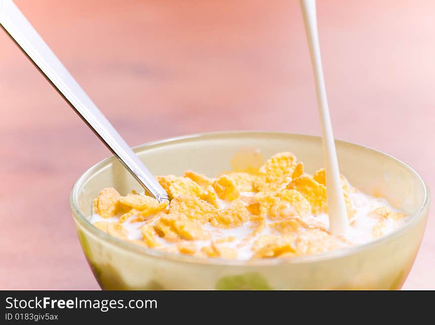 Corn flakes with milk and spoon on the table