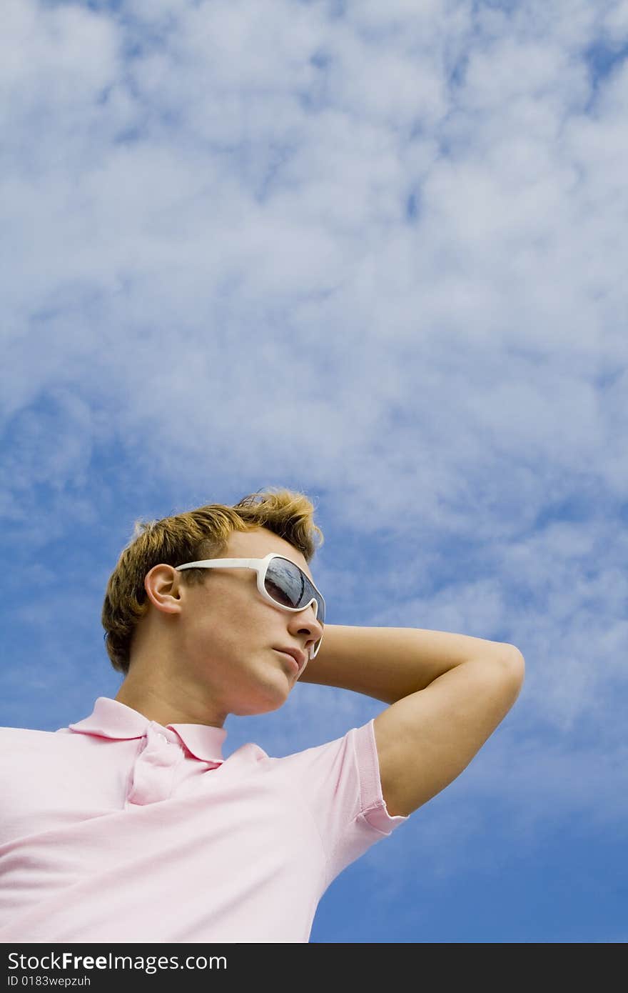 Portrait of a young man in sunglasses over blue sky