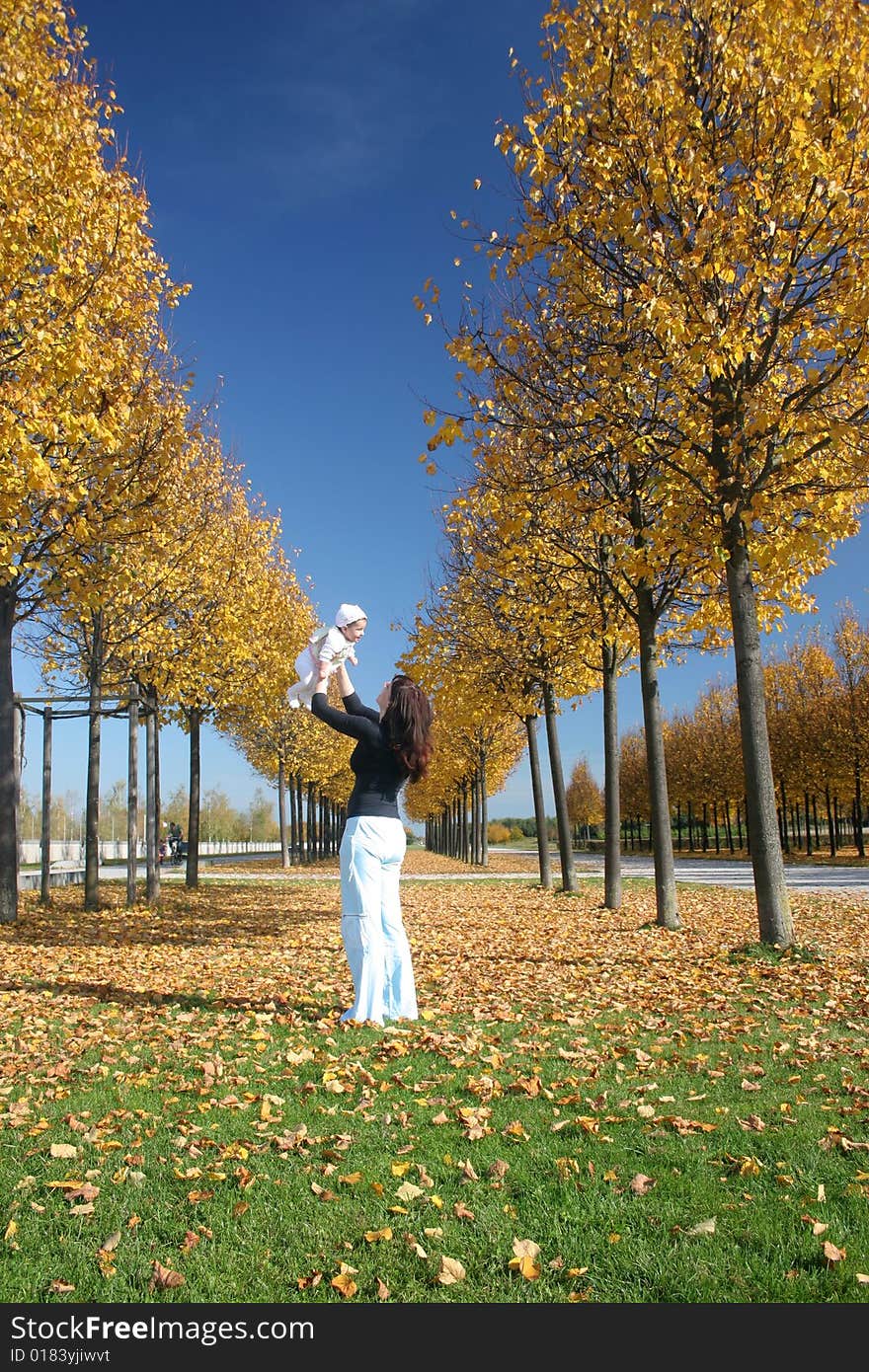 Mother and daugther playing in the park on a sunny autumn day