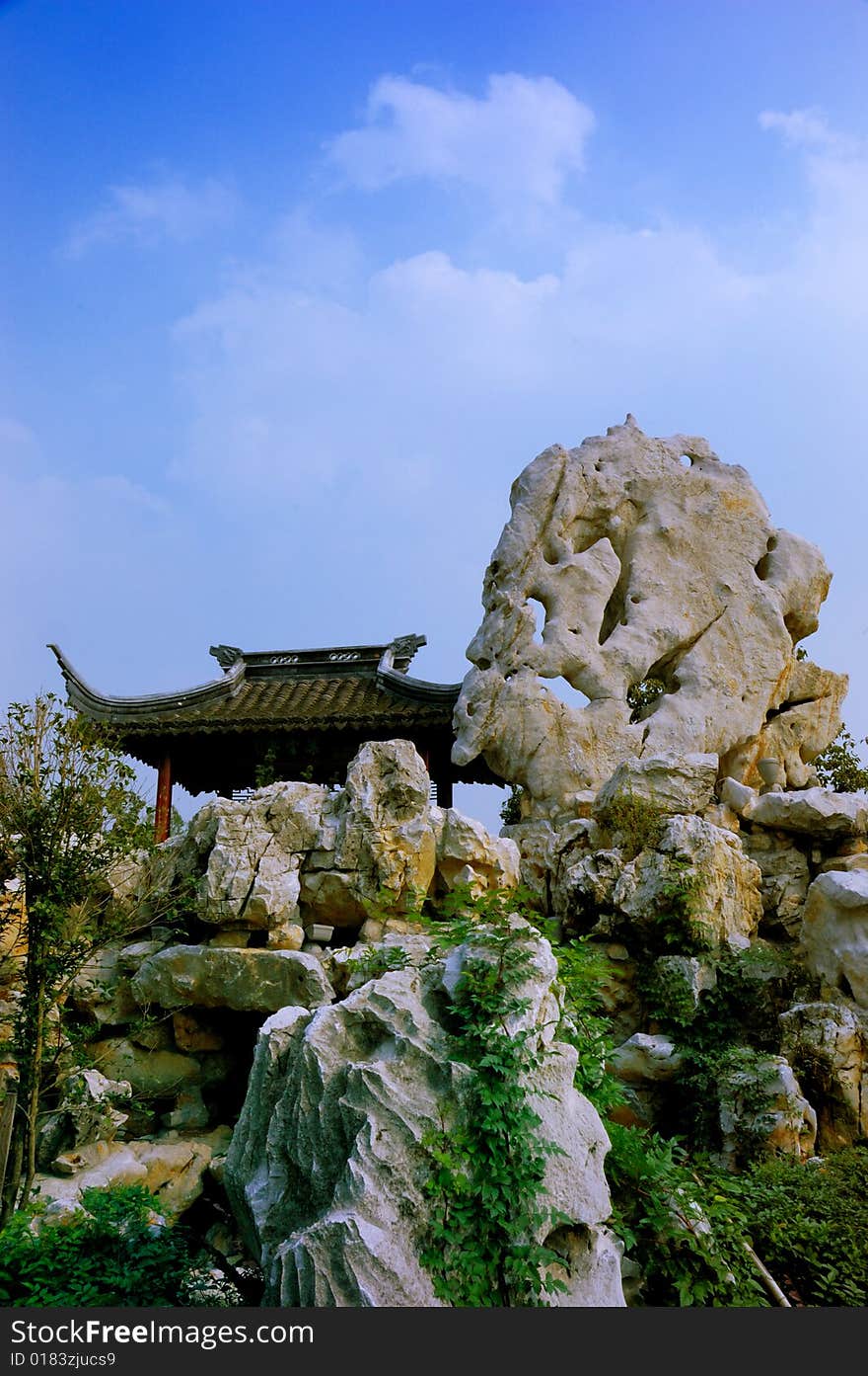 A chinese traditional gloriette on artistic stone hill under blue sky and white cloud. A chinese traditional gloriette on artistic stone hill under blue sky and white cloud.