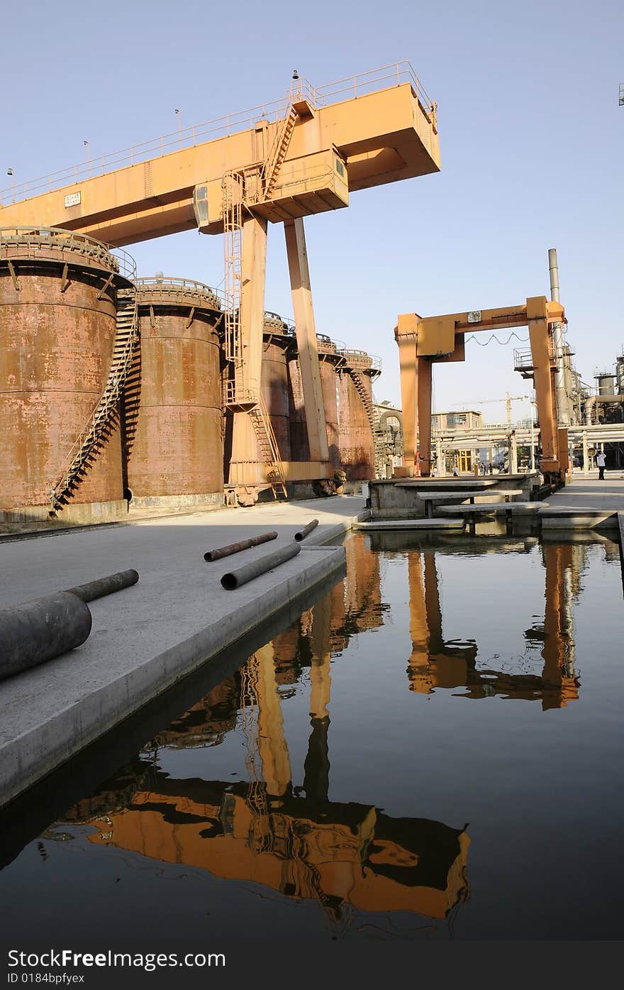 Crane and oil tanks in the factory with reflections. Crane and oil tanks in the factory with reflections