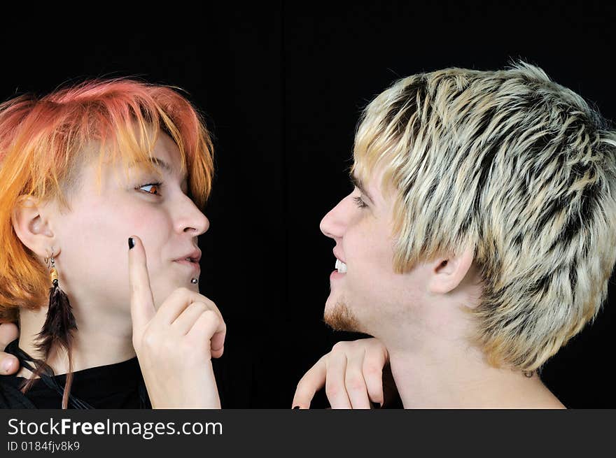 Young informal red-eyed girl wants to touch guy's nose, on black background. Young informal red-eyed girl wants to touch guy's nose, on black background