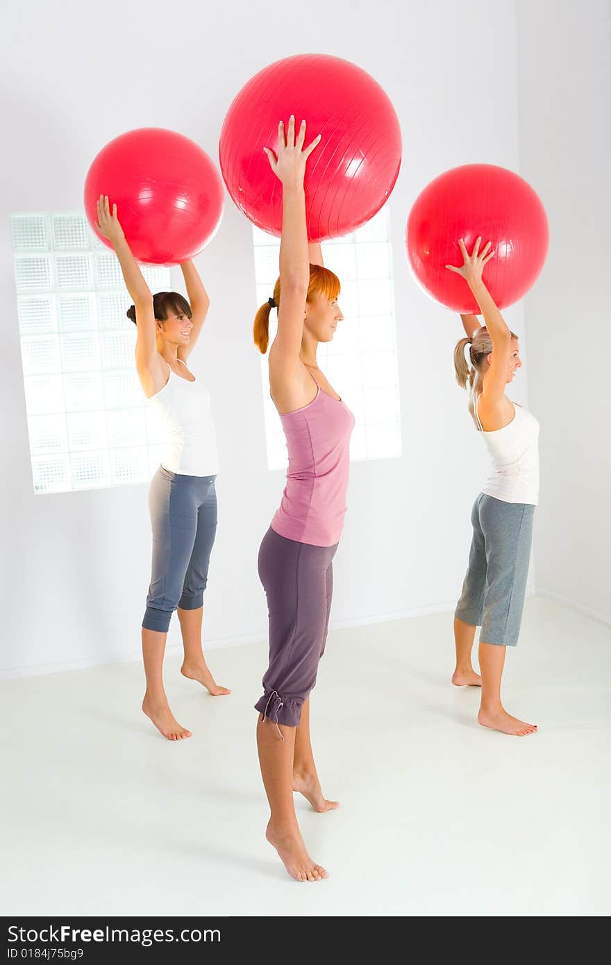 Group of women doing fitness exercise with big ball. They're looking at camera. Side view. Group of women doing fitness exercise with big ball. They're looking at camera. Side view.