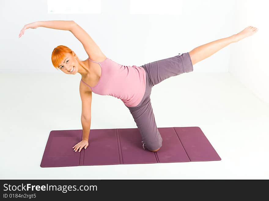 Young woman doing fitness exercise on mat. She's looking at camera. Young woman doing fitness exercise on mat. She's looking at camera.