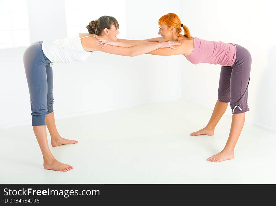 Two young women doing stretching exercises. Two young women doing stretching exercises.