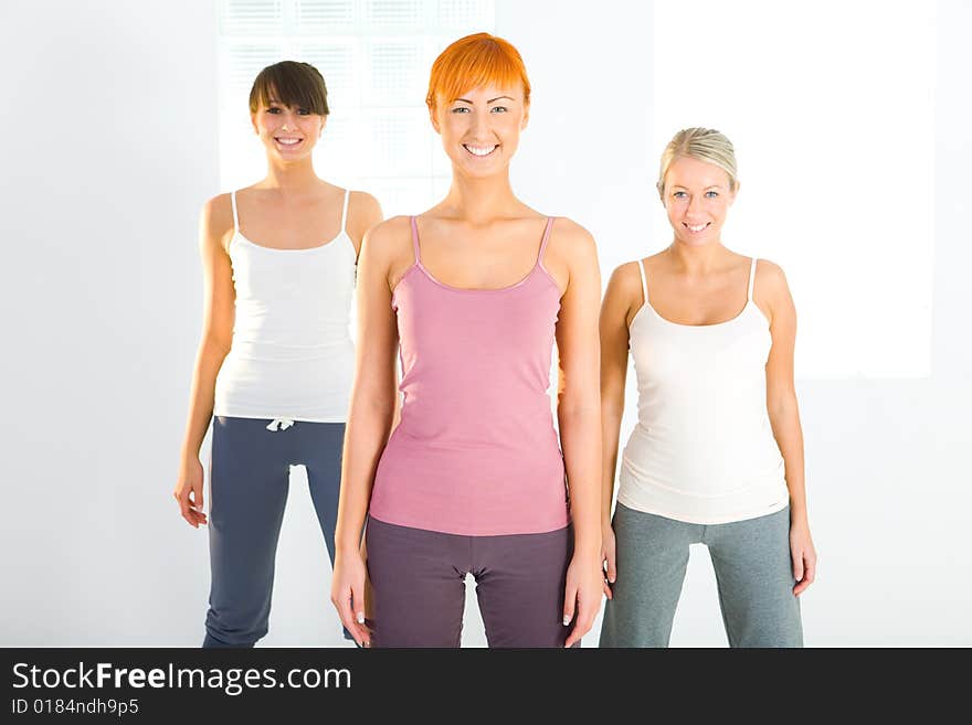 Three beautiful women dressed sportswear standing and looking at camera. Front view. Three beautiful women dressed sportswear standing and looking at camera. Front view.