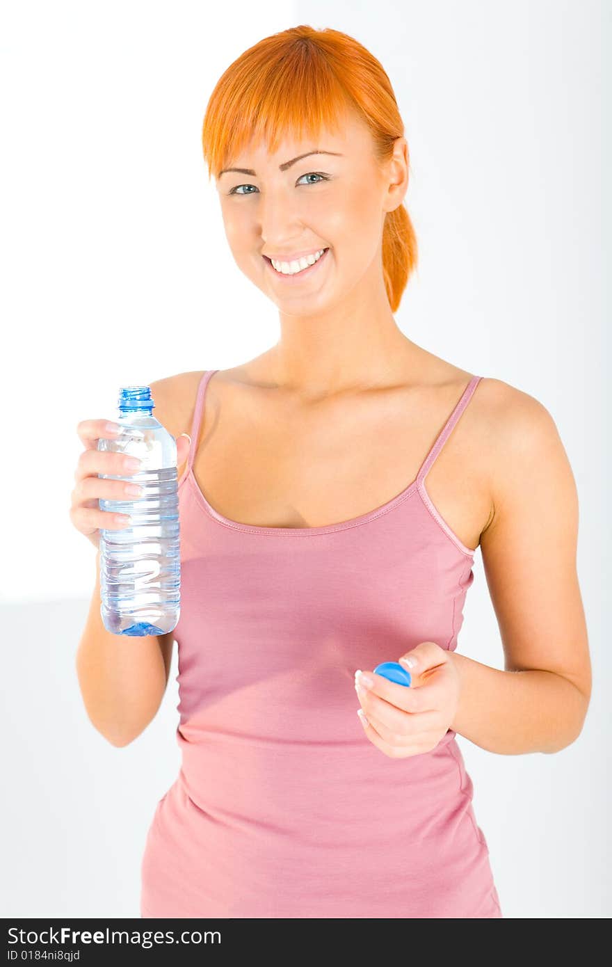 Young woman dressed sportswear holding water bottle. She's smiling and looking at camera. Front view. Young woman dressed sportswear holding water bottle. She's smiling and looking at camera. Front view.