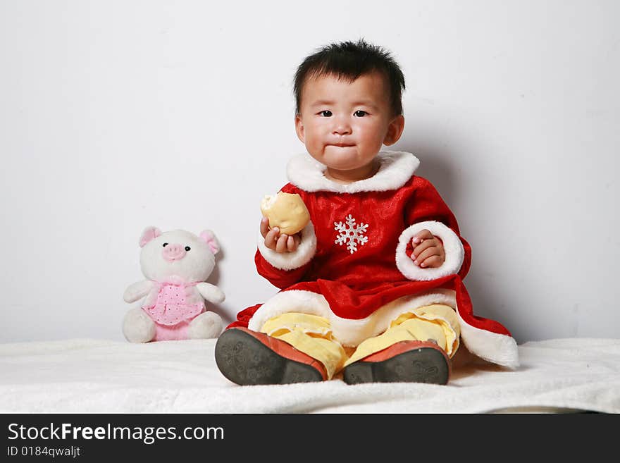 Santa baby eating bread ,some toy arround her