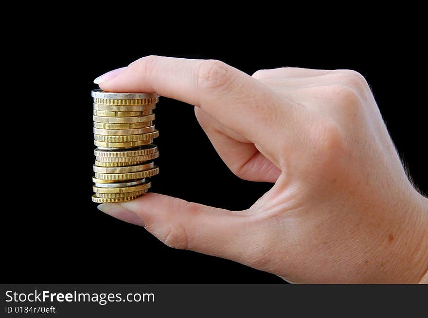 An Isolated to black image of a stack of coins held between fingers. An Isolated to black image of a stack of coins held between fingers