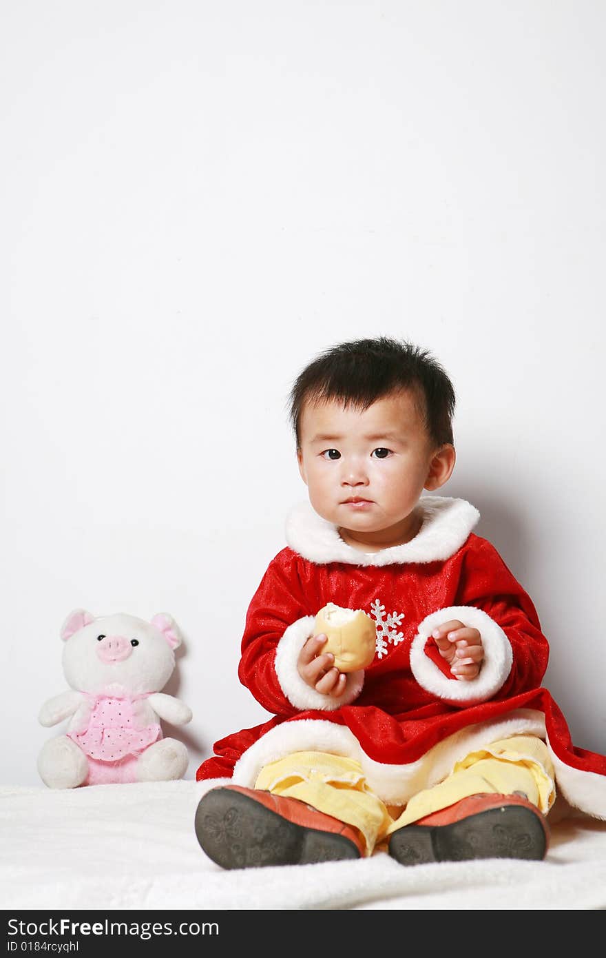 Santa baby in red dress with stuffed toy.