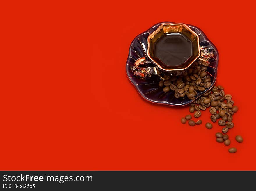 Coffee beans and a cup of coffee lying on the red background. Coffee beans and a cup of coffee lying on the red background