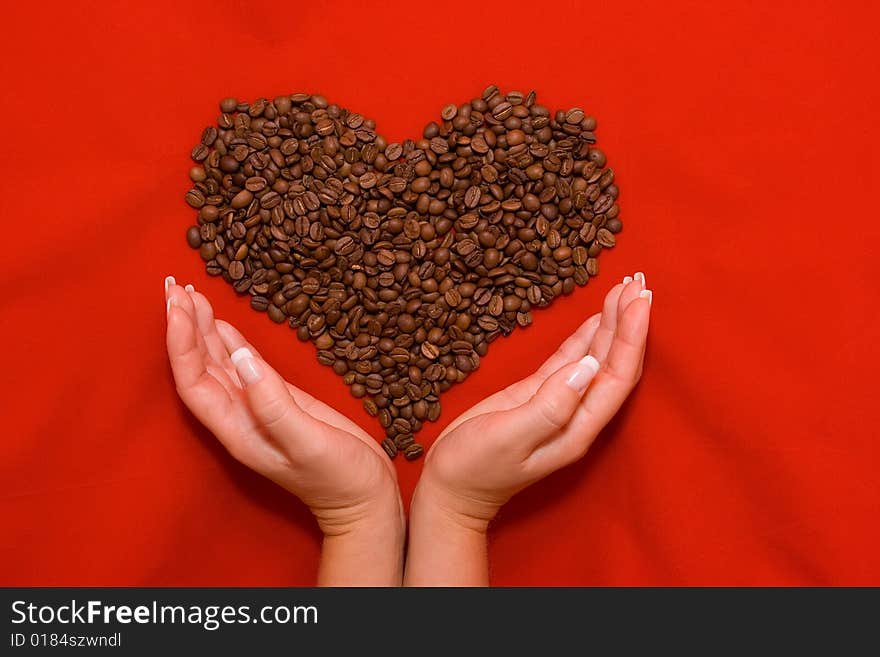 Heart made of coffee beans lying on the red background. Heart made of coffee beans lying on the red background