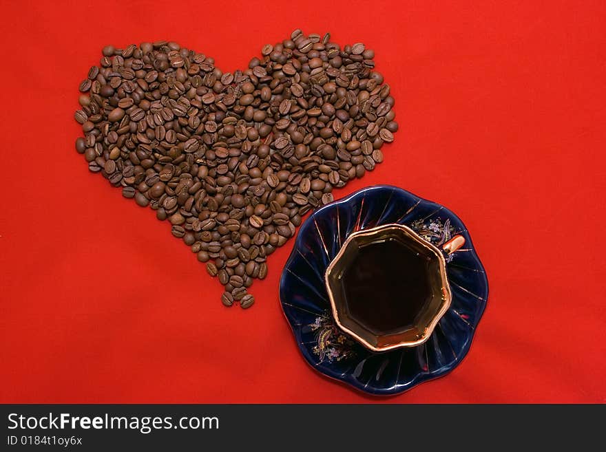 Heart made of coffee beans lying on the red background. Heart made of coffee beans lying on the red background