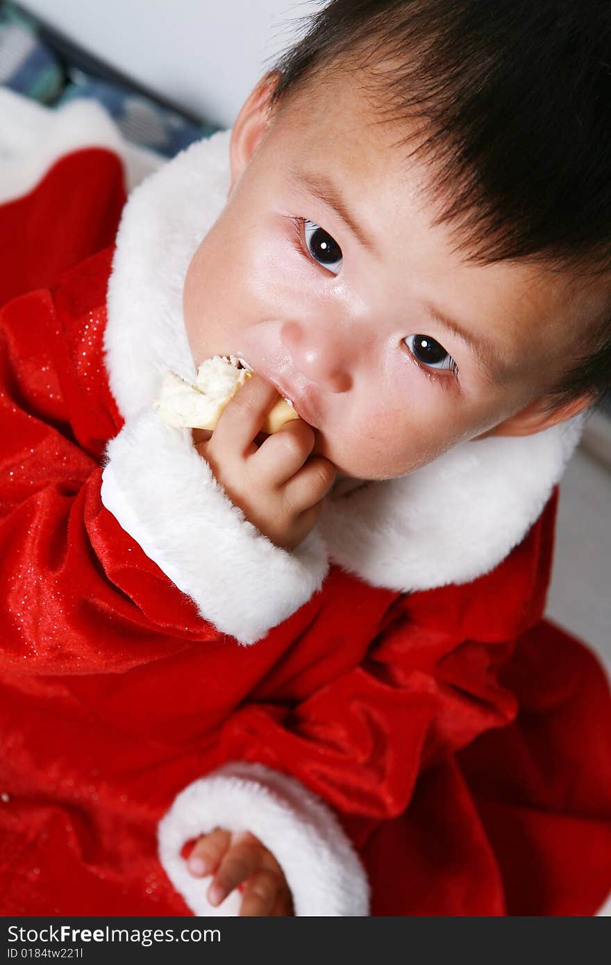 Santa baby in red dress eating.