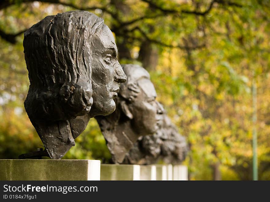 Sculptures of polish historical scientists in a park in autumn scenery.